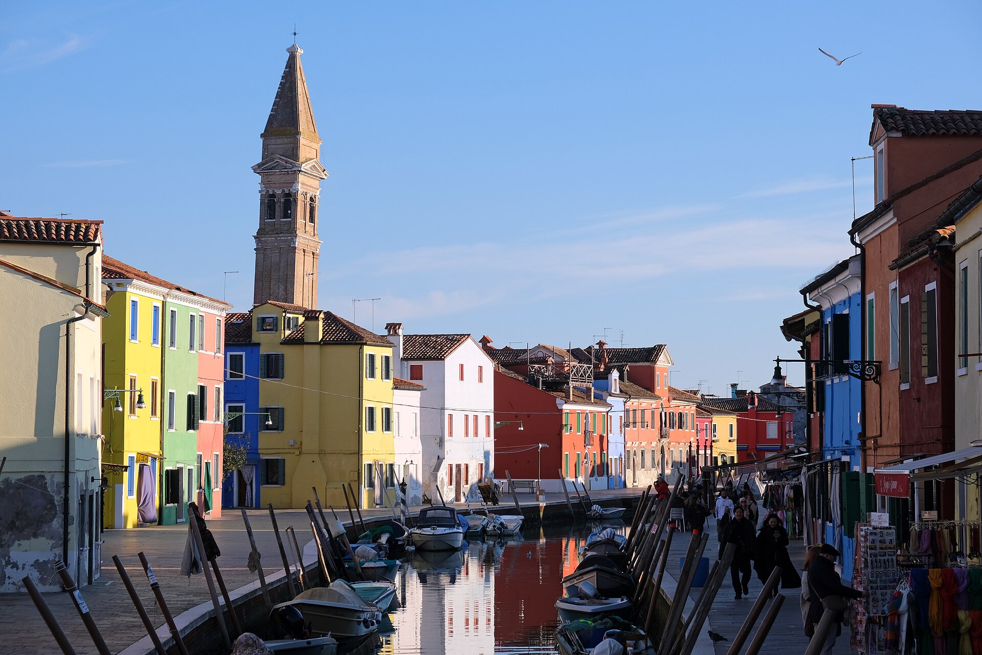 Fargerike hus, båter og kirketårn langs en kanal på Burano i Venezia
